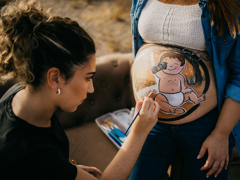 Mar maquillando a una embarazada con la técnica de belly painting.